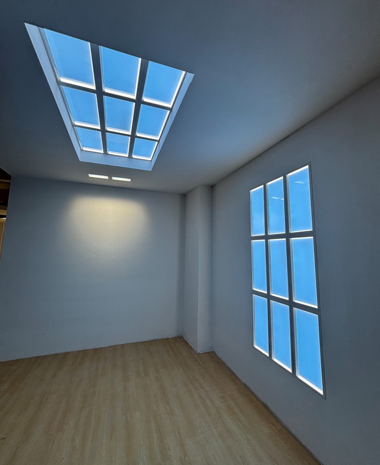 Blue-lit ceiling and wall panels arranged like skylights and windows in an empty white room